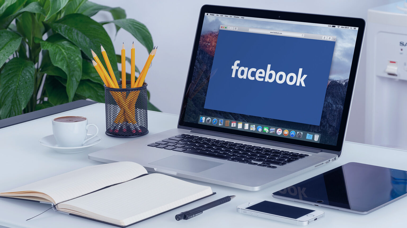 Laptop displaying Facebook beside campaign planning notes and a tablet